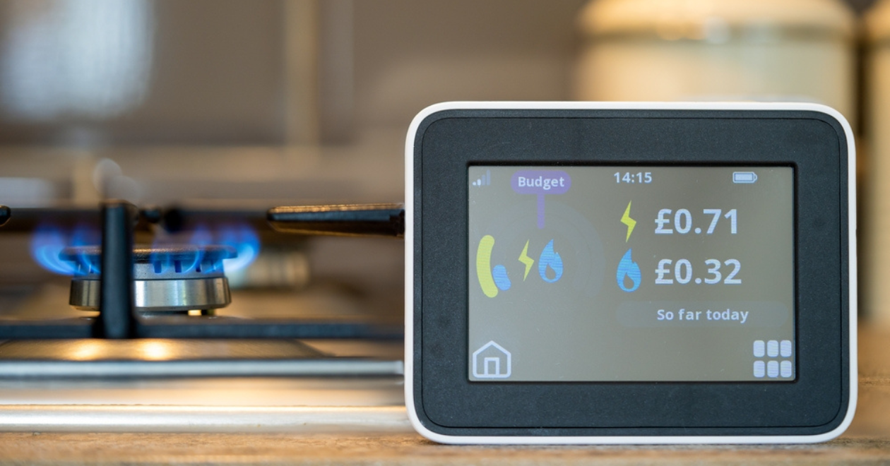 household digital smart meter against a background of a gas flame on a cooker