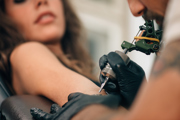 Tattooist tattooing a persons arm