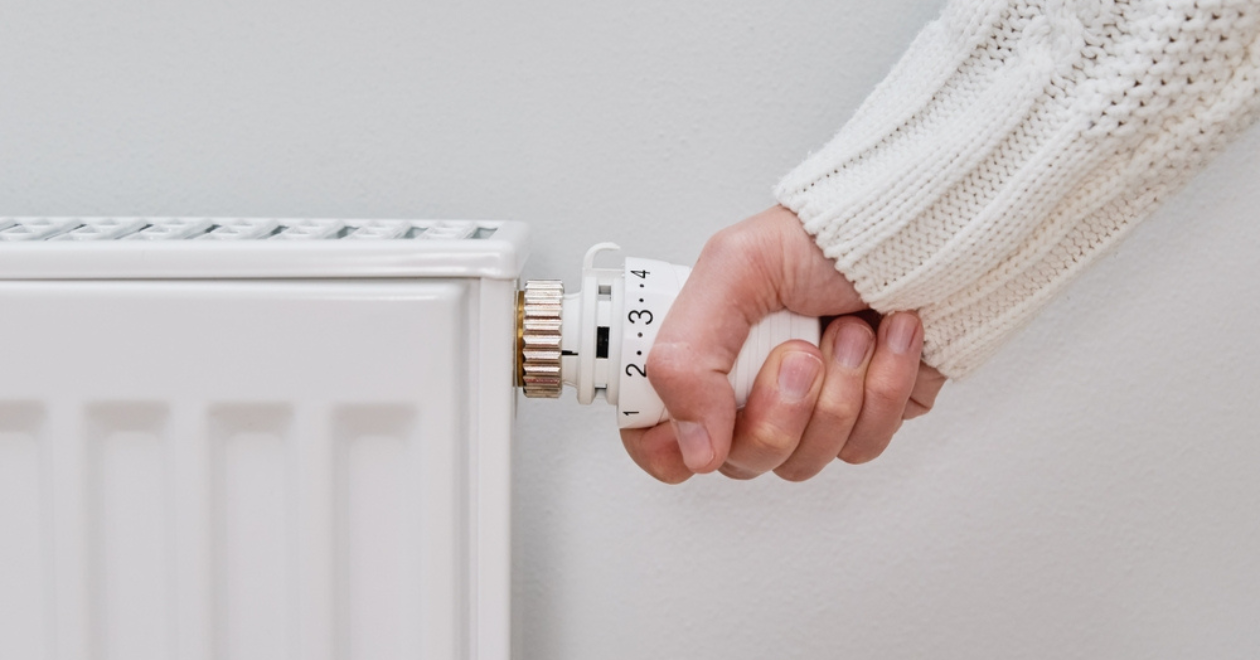 Woman adjusting temperature on heating radiator, Energy crisis concep