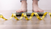 Feet standing on scales with measuring tape in foreground