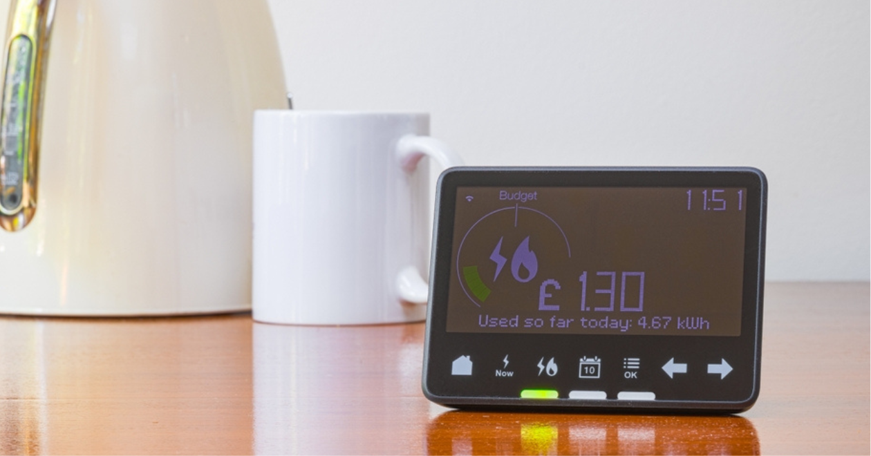 Smart meter placed on a table with a kettle and a mug, concept 