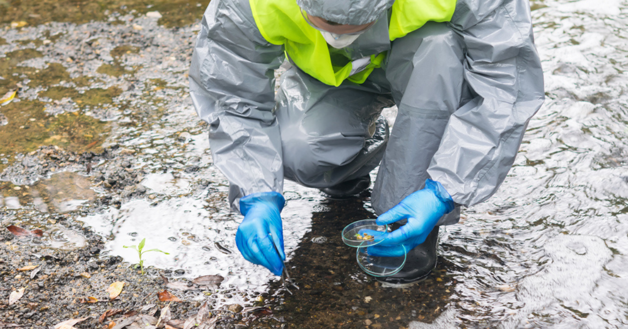 Person in protective suit taking sample from river