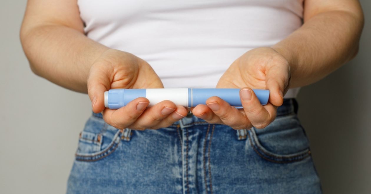 Blue Injection pen in female hand closeup. Diabetes and Weight Loss concept.